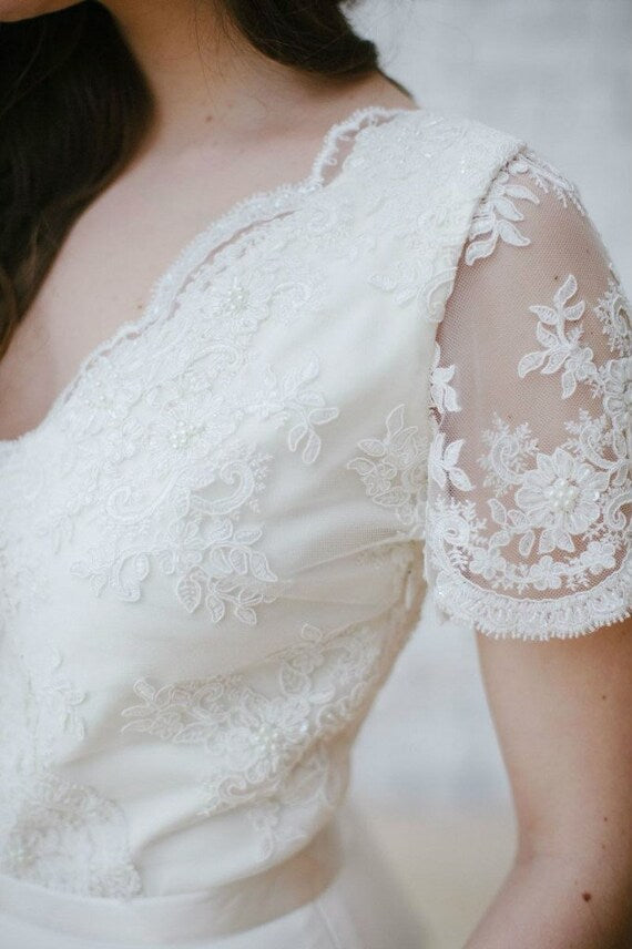 Close-up of Flora's V-neckline, floral lace, and pearl beading
