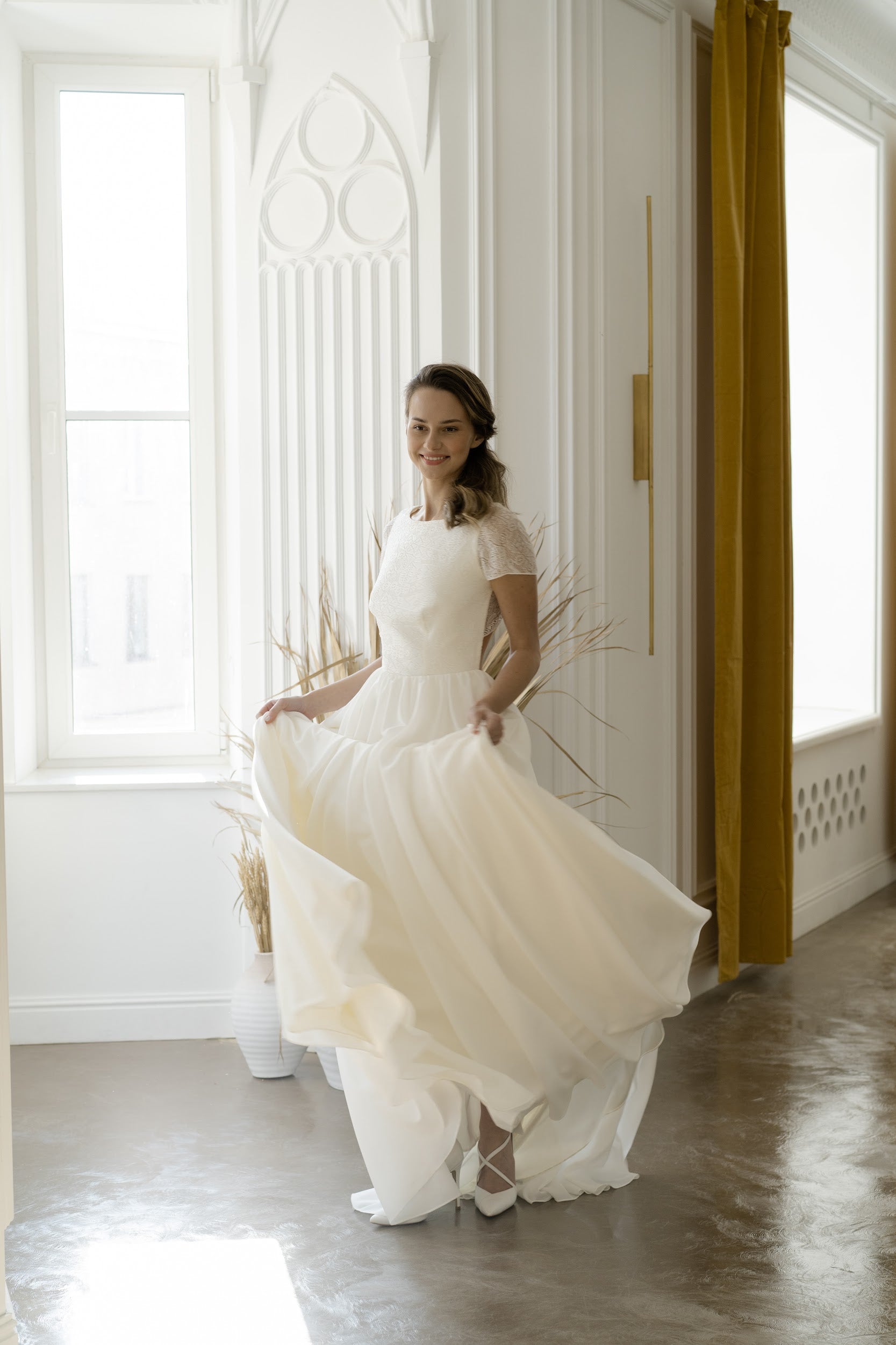 Bride holding the chiffon skirt of Odalis wedding dress, front view