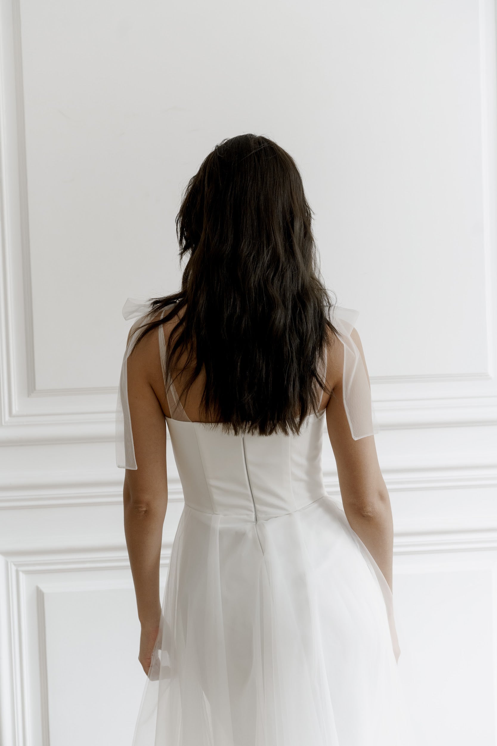 Back view of a midi tulle wedding dress with a zip back and bow straps