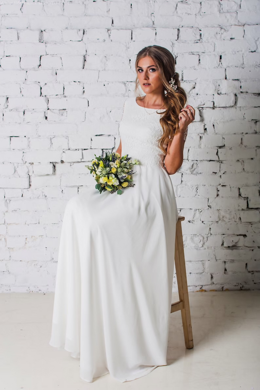 Bride seated in Camille lace wedding dress holding a bouquet