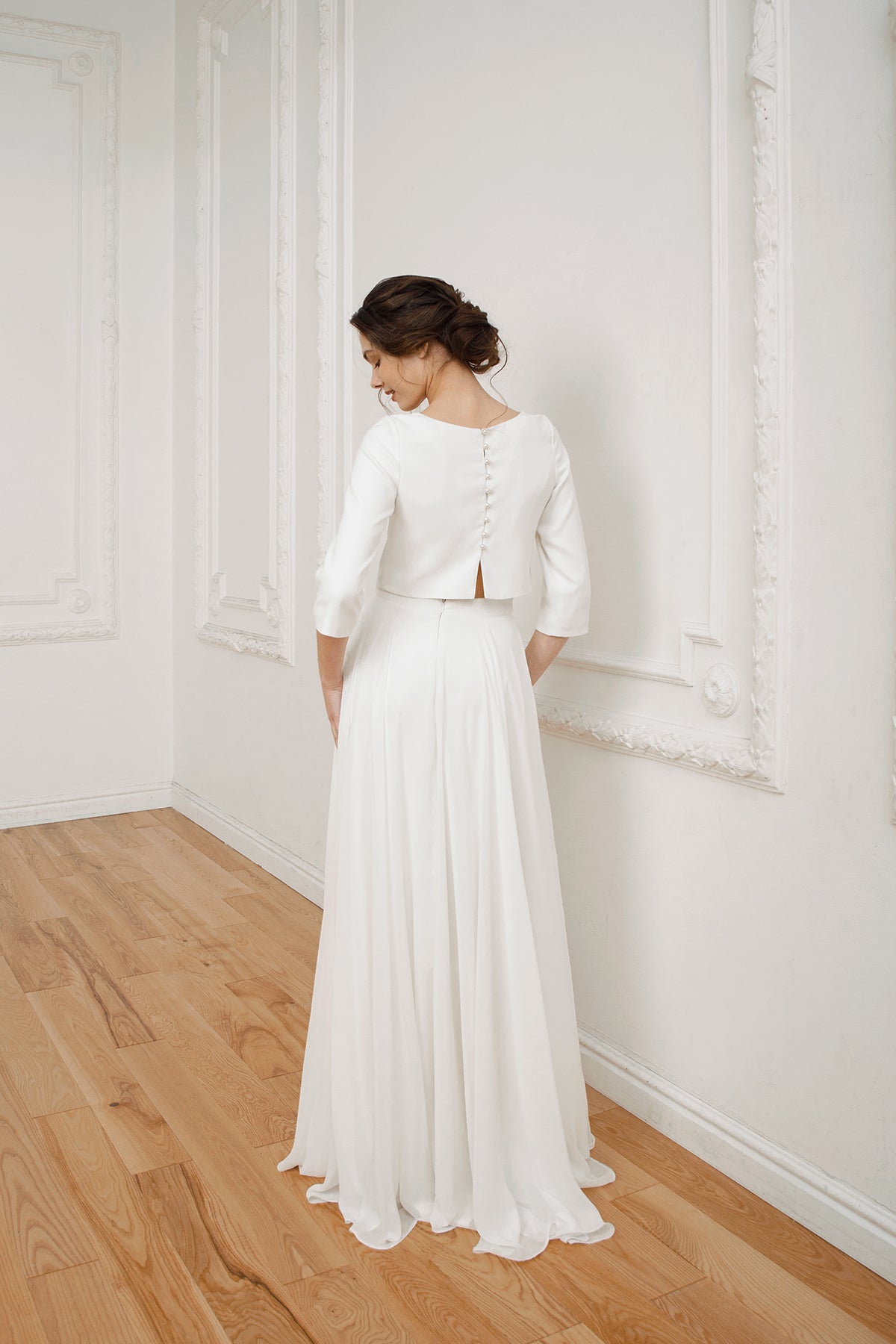 Back view of a two-piece wedding dress with a pearl-button crop top and high-low skirt