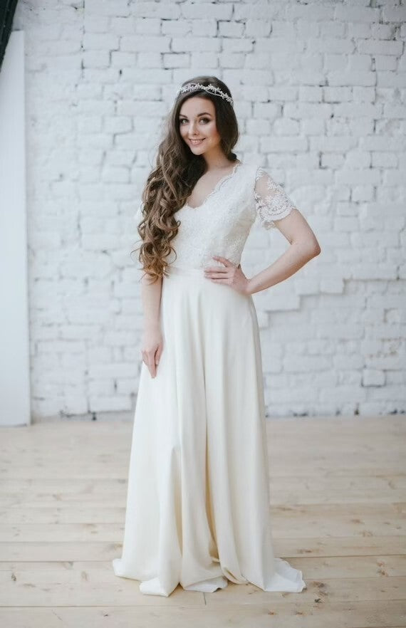 Flora wedding dress, full front view against a white brick wall
