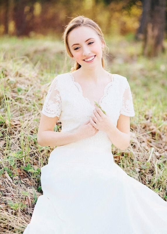 Bride in Flora lace wedding dress seated in a meadow