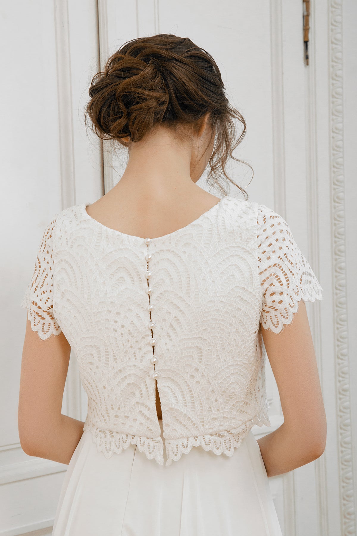 Keyhole button-back detail on a scalloped lace crop top