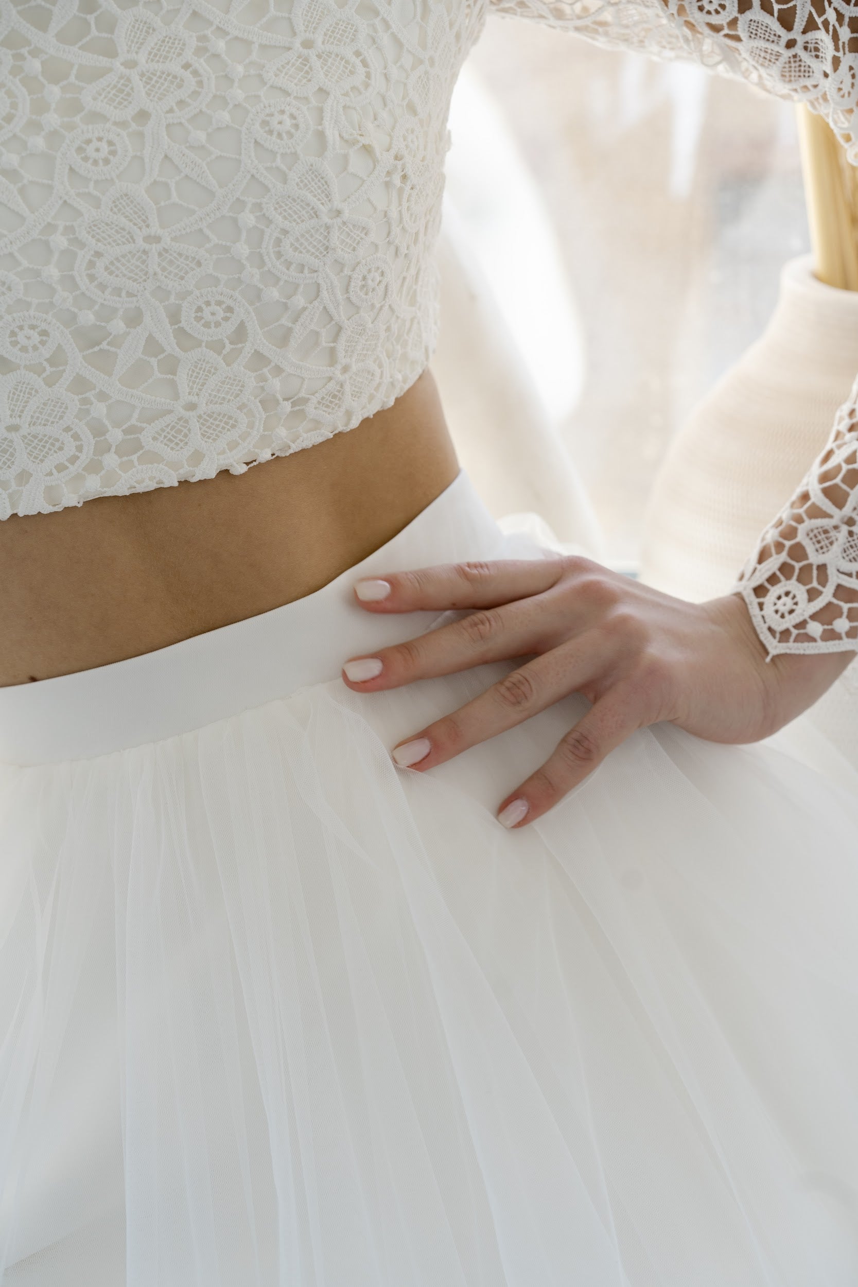 Detail of Margaux's bare waist between lace top and tulle skirt
