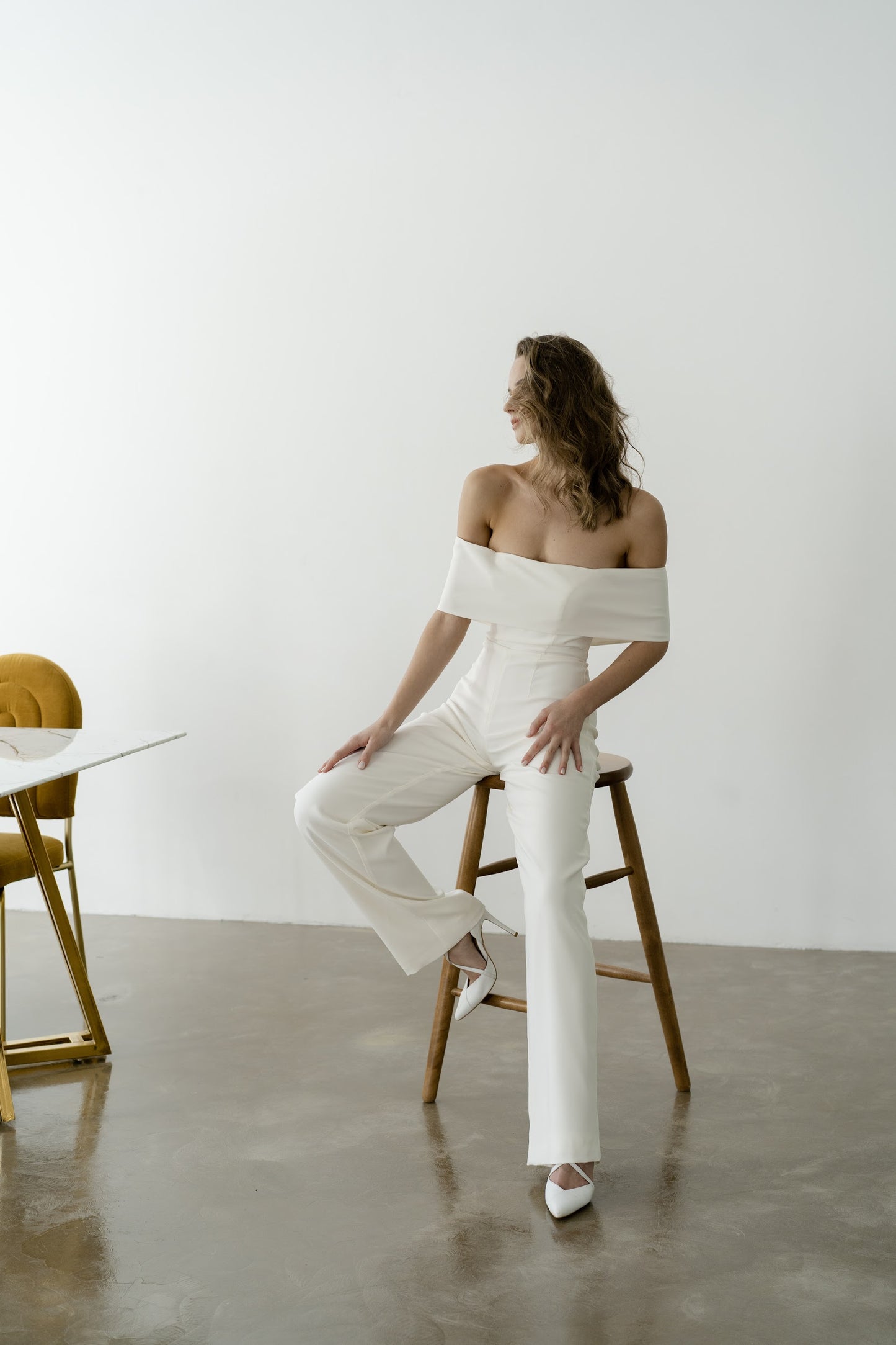 Bride in an off-the-shoulder royal crepe bridal jumpsuit with wide trouser legs
