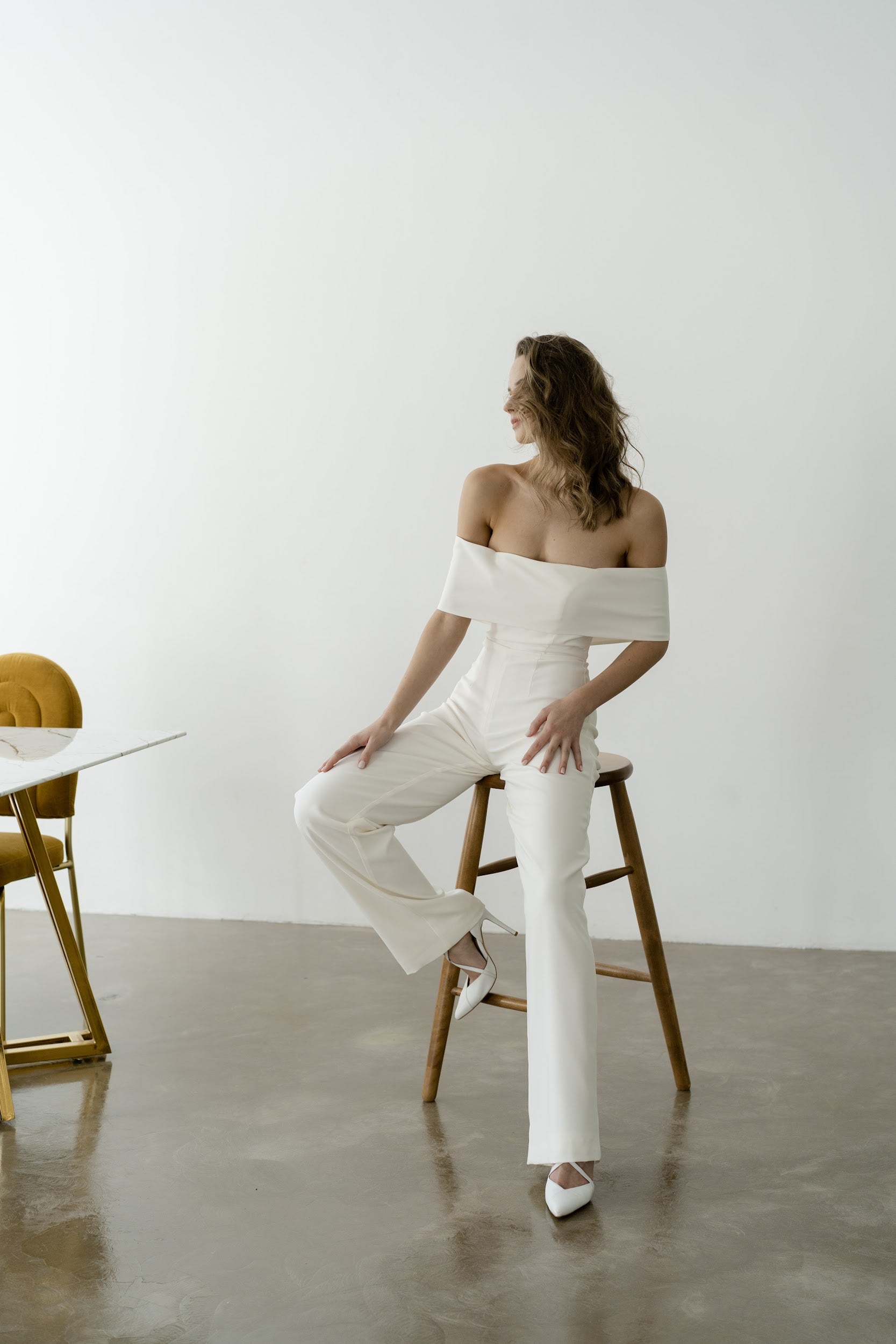 Bride in an off-the-shoulder royal crepe bridal jumpsuit with wide trouser legs
