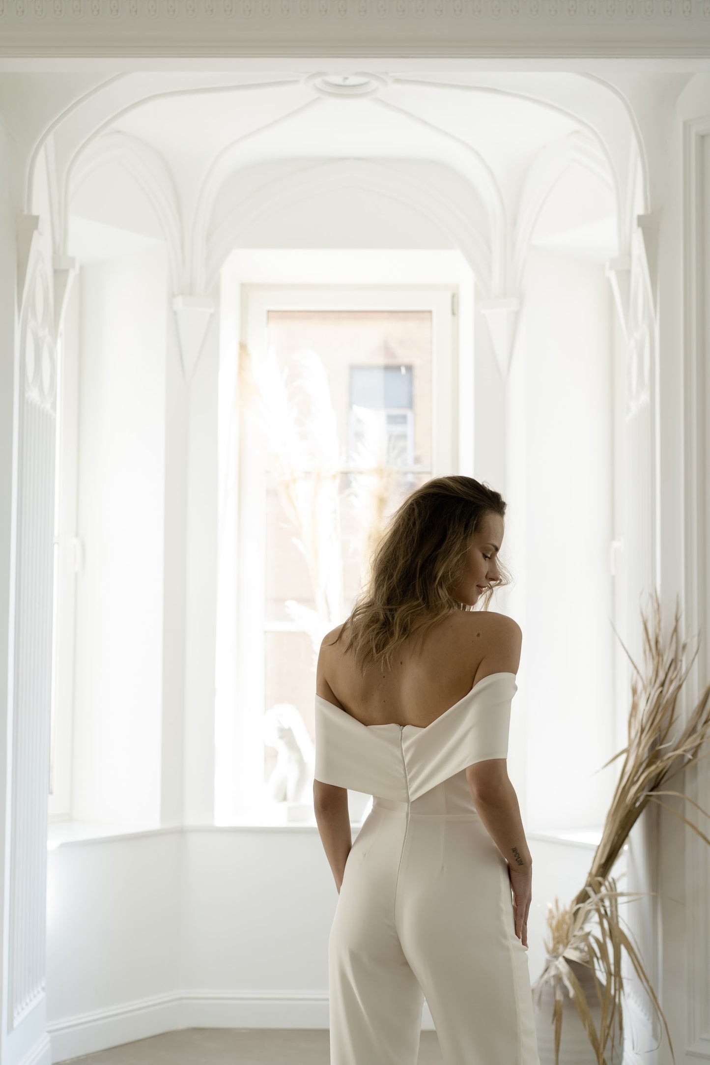 Off-the-shoulder neckline and button back of a bridal jumpsuit