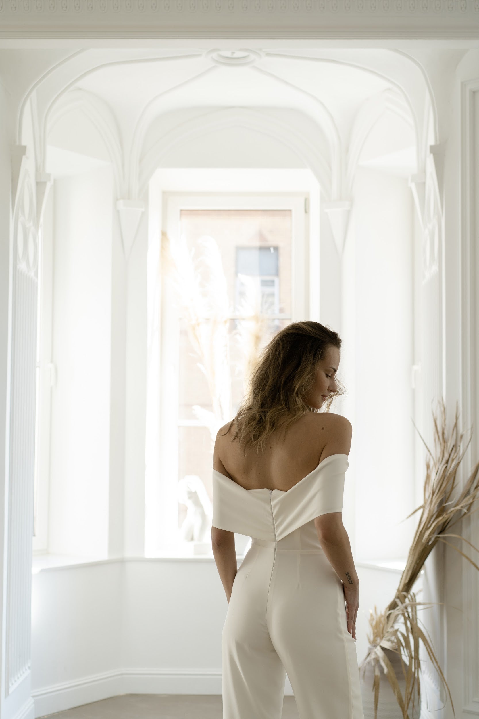 Off-the-shoulder neckline and button back of a bridal jumpsuit