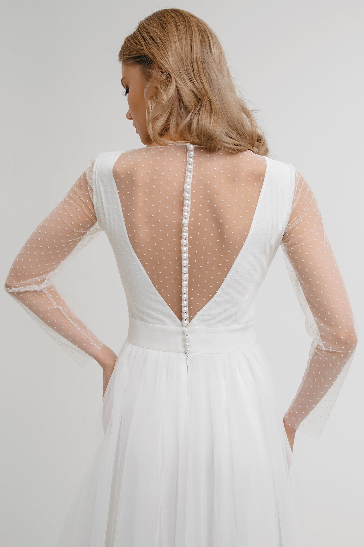 Back detail of White Orchid wedding dress showing pearl buttons down the sheer V back
