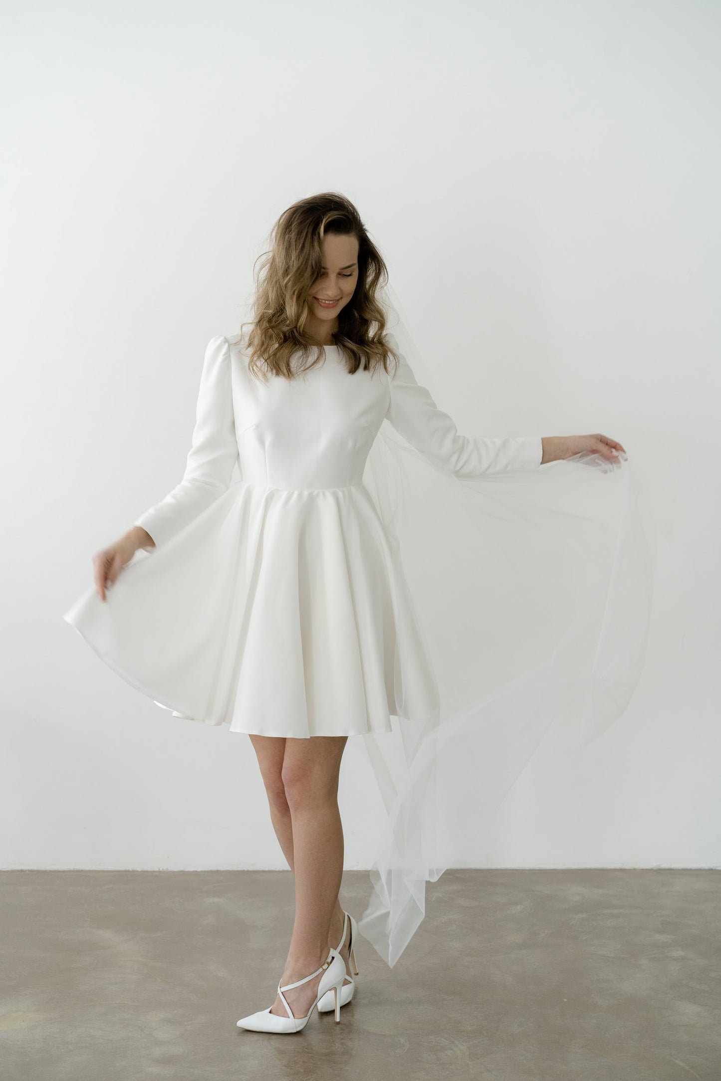 Bride in a short royal crepe wedding dress with long sleeves and a full skirt