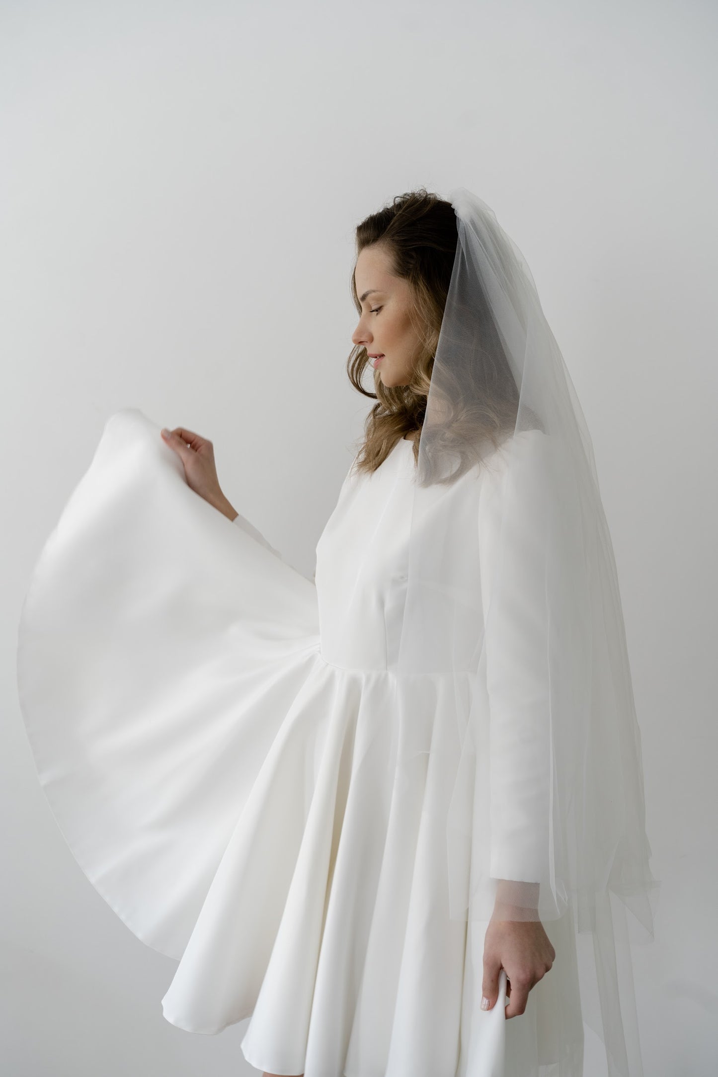 Side view of a short long-sleeve wedding dress with a veil