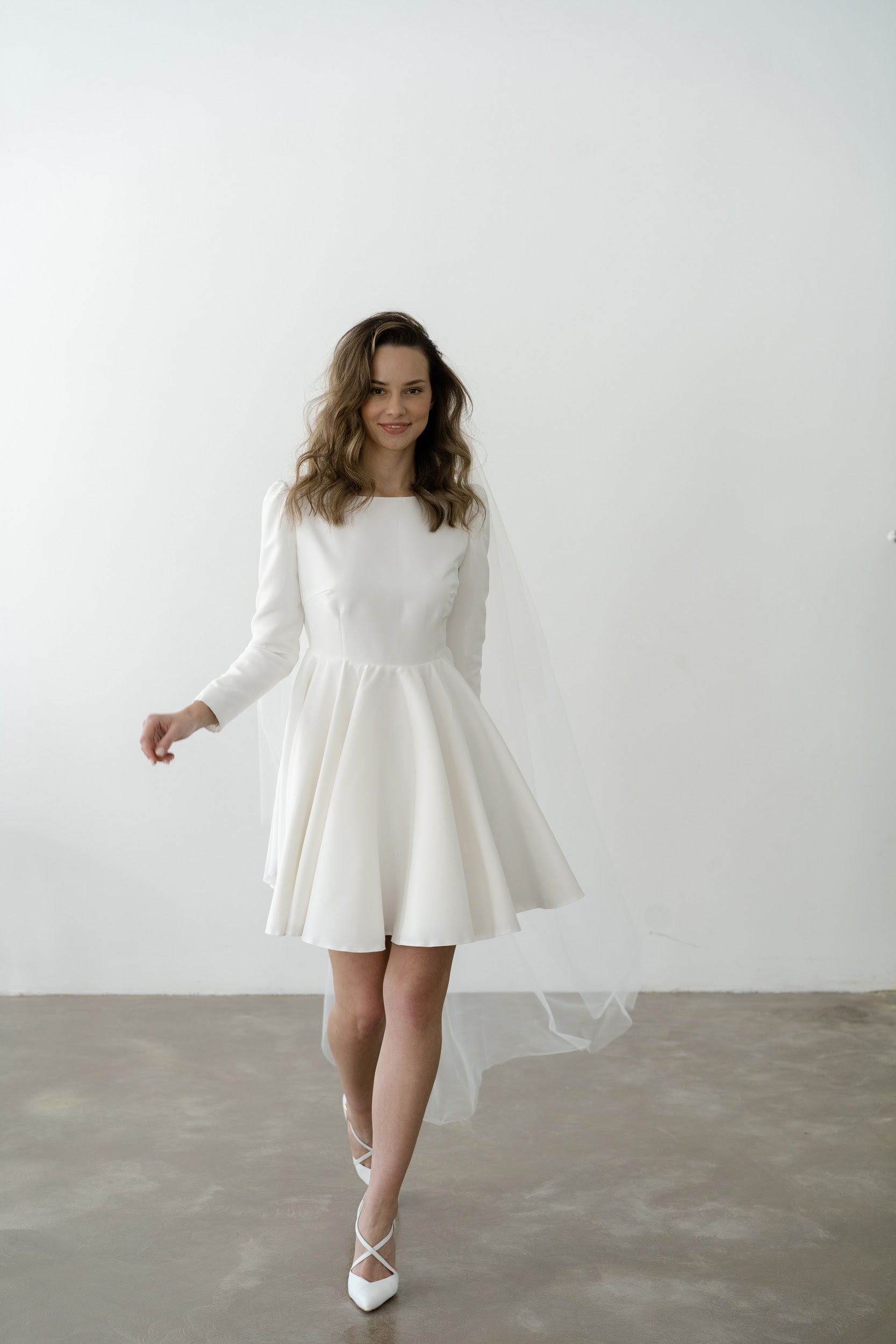 Bride in a short long-sleeve wedding dress with a veil